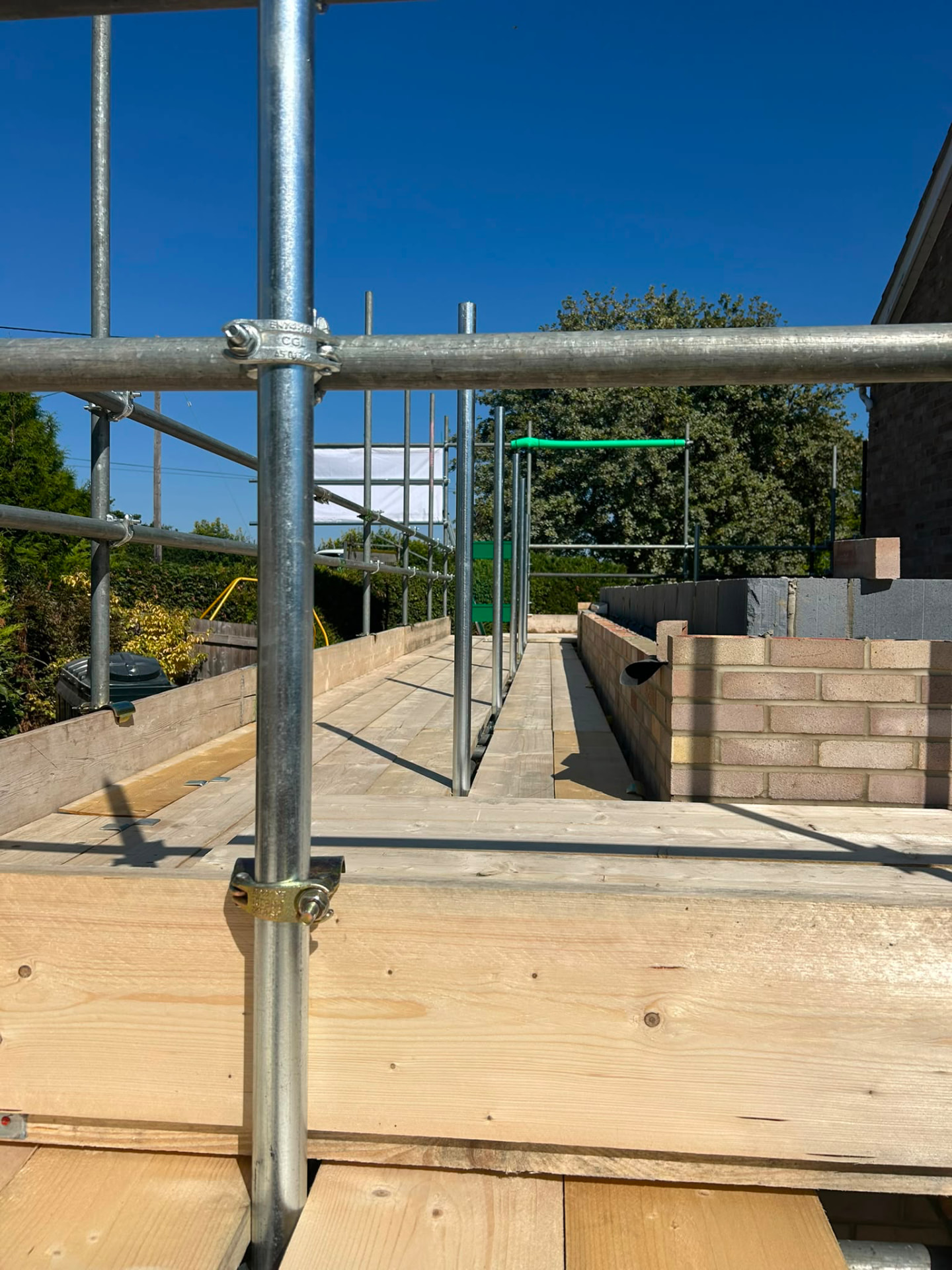 Close up of scaffold guardrails and boarded platform at brickwork level on a Hampshire extension build